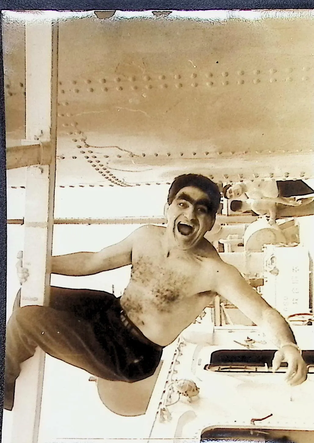 A sepia family-album scan of a young Wild Bull Curry, hanging one-armed off rigging, mid-howl