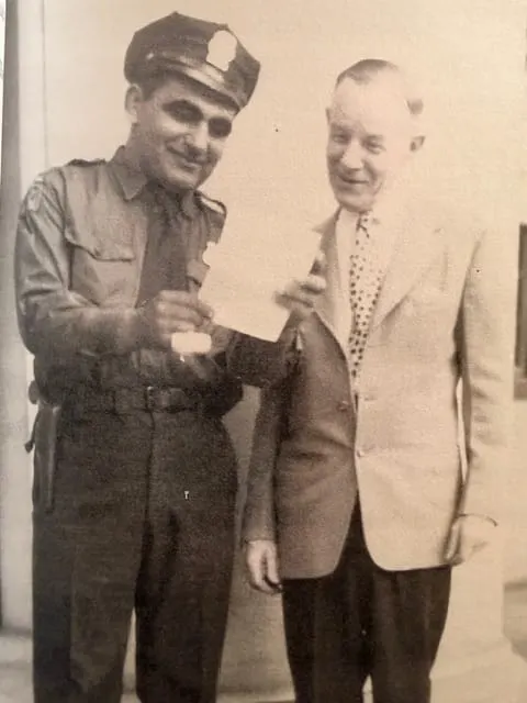 Fred Bull Curry in full Hartford Police Department uniform, cap and badge, holding a document with another man, sepia family photograph